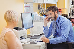 Doctor sitting at his desk and talking on phone