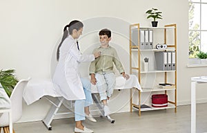 Doctor sitting on medical couch with child examining his heart or lungs with stethoscope