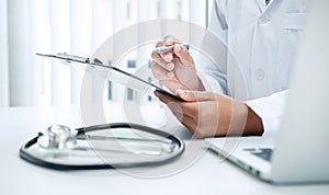 Doctor is sitting and reading medical report in his hospital office