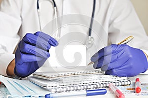 the doctor is sitting at the table wearing blue gloves and holding a white card in his hand