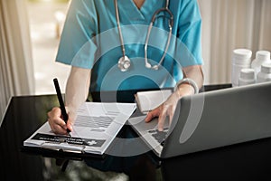 Doctor sitting at table and writing on a document report in hospital office. Medical healthcare staff and doctor service