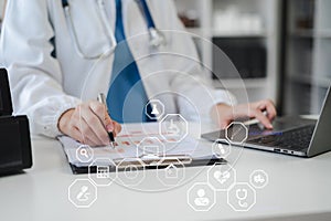 Doctor sitting at table and writing on a document report in hospital office. Medical healthcare staff and doctor service