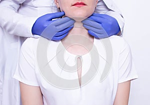 Doctor specialist diagnoses palpation on the throat of the caucasian girl for the presence of enlarged lymph nodes and photo