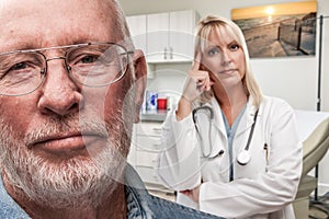 Doctor Standing Behind Troubled Senior Adult Man In Office