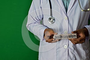 Doctor standing on Green background. Hold the Health Care Reform paper text.