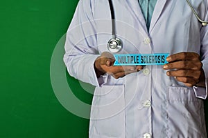 Doctor standing on Green background. Hold the Multiple Sclerosis paper text.