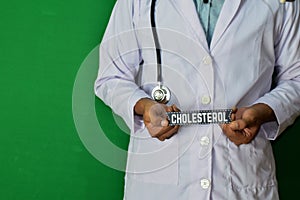 Doctor standing on Green background. Selective focus in hand. High Colesterol paper text. photo