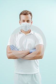 Doctor standing with hands crossed on light blue background. Healthy concept