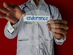 A doctor standing, Hold the endurance paper text on red background. Medical and healthcare concept