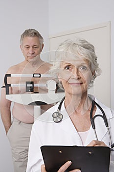 Doctor Standing With Patient Checking Weight In Background