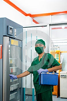 Doctor in sterile clothes and mask carrying a blood bag box