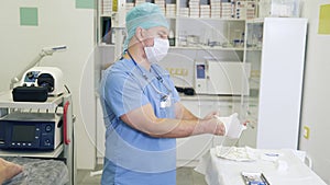 Doctor in sterile clothes and mask puts on gloves before sclerotherapy procedure.