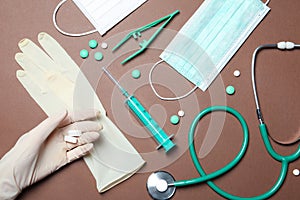 Doctor in sterile glove with medical items on color background
