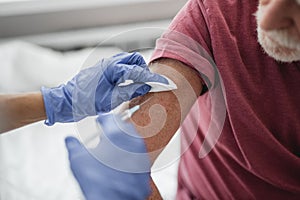 Doctor in sterile gloves giving injection in man arm
