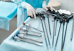 Doctor in sterile gloves taking laparoscopic instrument