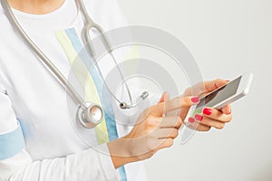 Doctor with stethoscope around her neck using phone