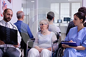 Doctor with stethoscope communicating to disabled senior woman radiography