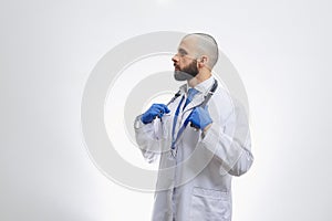 A doctor with a stethoscope in disposable gloves preparing to examine a patient