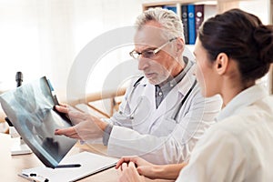 Doctor with stethoscope and female patient in office. Doctor is showing x-ray.