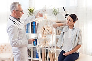 Doctor with stethoscope and female patient in office. Patient`s neck hurts.