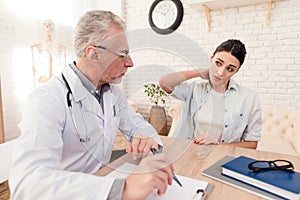 Doctor with stethoscope and female patient in office. Patient`s neck hurts.