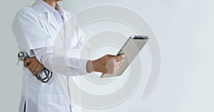Doctor with stethoscope in hand using a digital tablet on blue background, Healthcare medical, and medicine