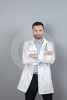 Doctor with a stethoscope on his neck standing near the wall