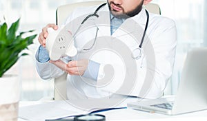 Doctor with stethoscope holding piggy bank.