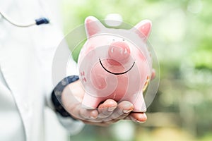 Doctor with Stethoscope holding piggy bank for saving money health care cost, medical financial