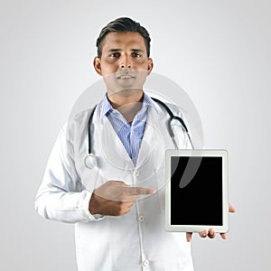 Doctor with stethoscope pointing finger to the blank tablet pc s