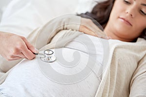 Doctor with stethoscope and pregnant woman