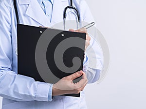 Doctor with stethoscope in white coat holding clipboard, writing medical record diagnosis, isolated on white background, close up