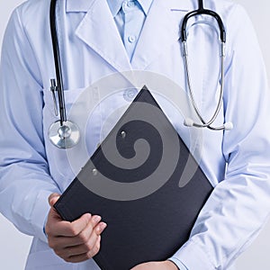 Doctor with stethoscope in white coat holding clipboard, writing medical record diagnosis, isolated on white background, close up