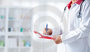 Doctor with stethoscope writing on a hospital cardboard