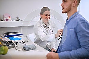Doctor with stetoscope listens patientÃ¢â¬â¢s heart photo
