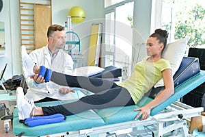 Doctor stretching woman leg on physiotherapy session