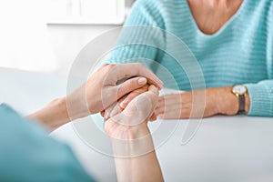 Doctor supporting elderly woman in clinic, closeup