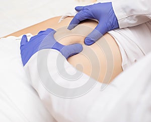 Doctor surgeon examines the stomach of a girl patient for the presence of umbilical hernia. Abdominal wall disease photo