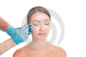 Doctor surgeon hand in gloves on patient face drawing cut line