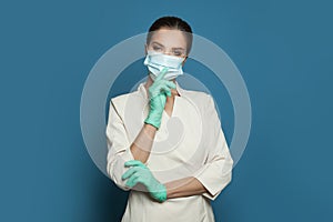 Doctor surgeon in protective medical mask and surgical gloves on blue background