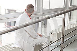 Doctor or surgeon is sitting thinkful at a window