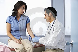 Doctor In Surgery Taking Female Patient's Pulse
