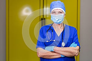 A doctor in surgical cap and stethoscope wearing nitrile gloves and a mask