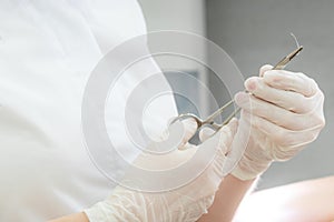 Doctor with surgical forceps holding a suture needle