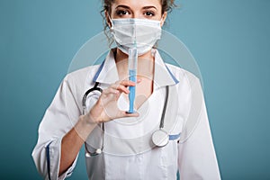 Doctor in syrgical mask showing syringe
