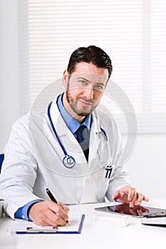 Doctor at table glancing at camera