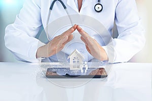 Doctor at the table with his hands to protect the icon the family and home.