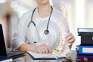 A doctor at the table holding a spin skeleton with pelvis part