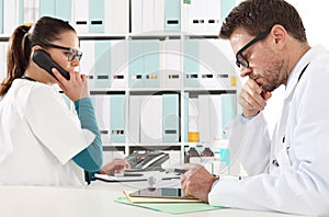 Doctor with the tablet and nurse at phone in medical office