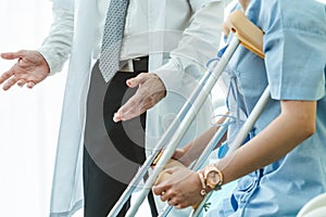 Doctor takes care of patient in crutch at hospital photo